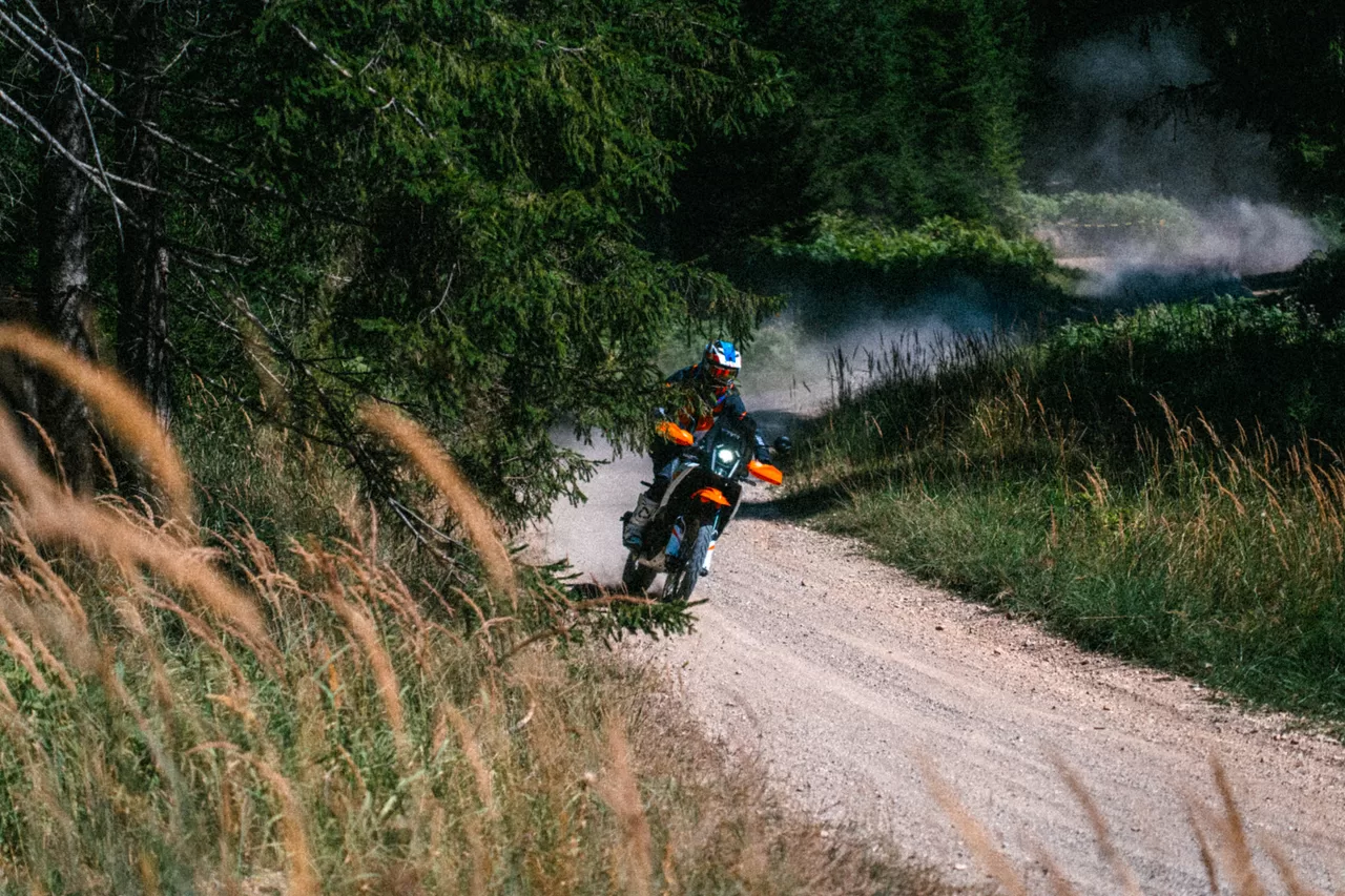 Motorradfahrer beim Beschleunigen aus einer staubigen Waldkurve