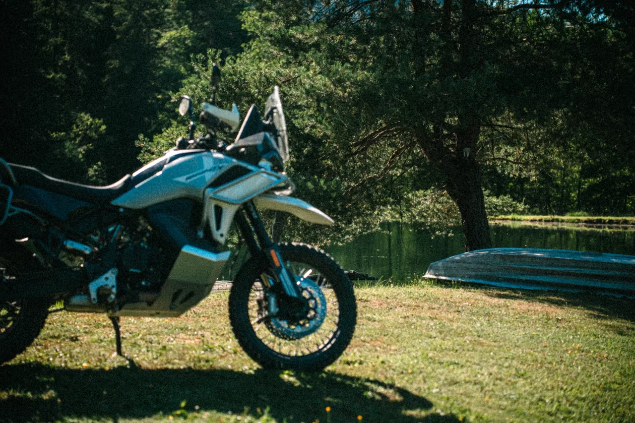 Blaues Adventure-Motorrad auf einer sonnigen Waldlichtung