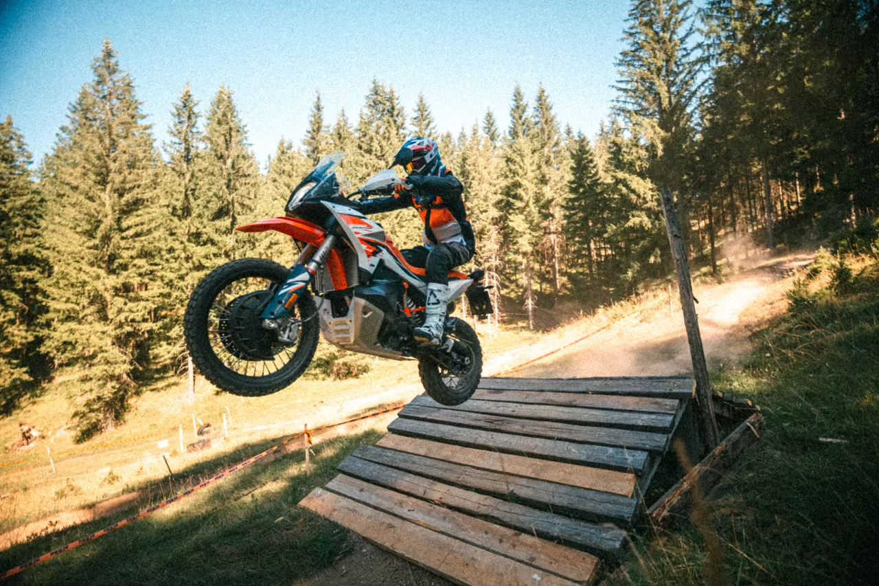 Oranges Adventure-Motorrad in der Luft über einer Holzrampe